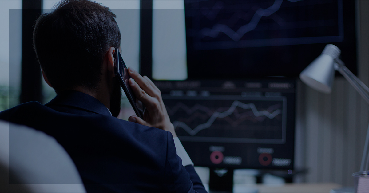 Homem sentado falando ao celular olhando um gráfico no Computador. | Qual é a importância das estratégias omnichannel?