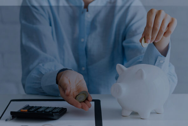 Mulher sentada guardando dinheiro no cofre. 4 passos para começar a economizar