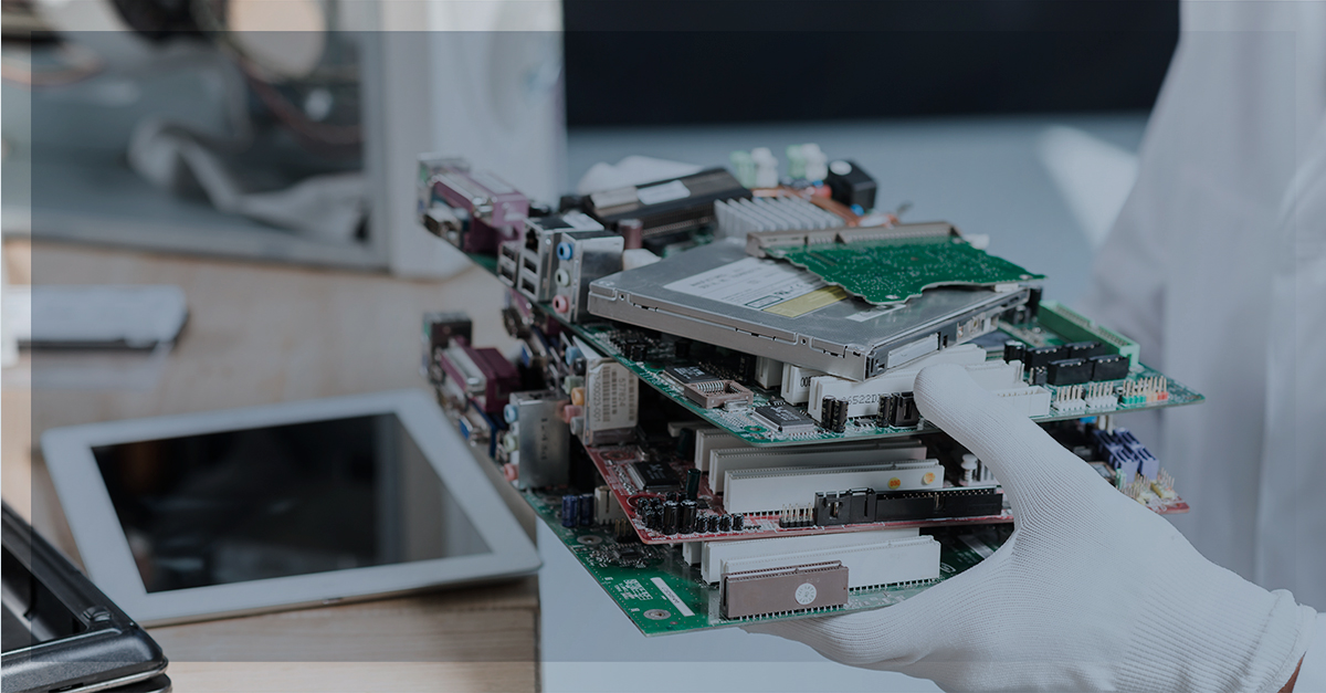 Mãos com luvas brancas seguram uma pilha de placas-mãe e componentes eletrônicos, destacando a importância da reciclagem responsável de gadgets antigos.