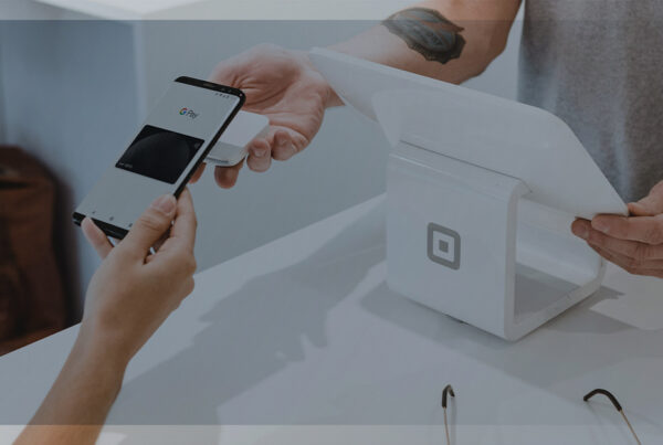 Pessoa realizando pagamento por aproximação com celular em máquina de ponto de venda, representando inovação no varejo.