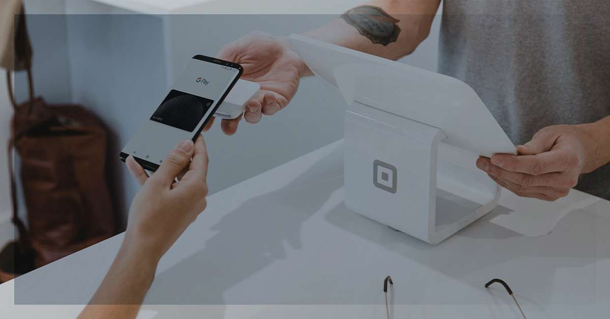 Pessoa realizando pagamento por aproximação com celular em máquina de ponto de venda, representando inovação no varejo.