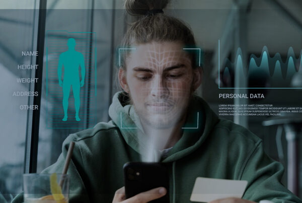 Jovem de cabelo preso em um coque utiliza o celular enquanto sua face é escaneada digitalmente, simulando uma coleta de dados biométricos com sobreposição de gráficos futuristas e informações pessoais.