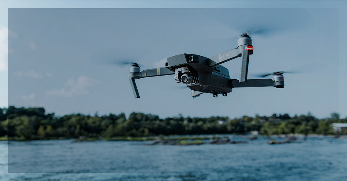 Drone voando sobre um rio com vegetação ao fundo, representando uso de tecnologia para logística e monitoramento.