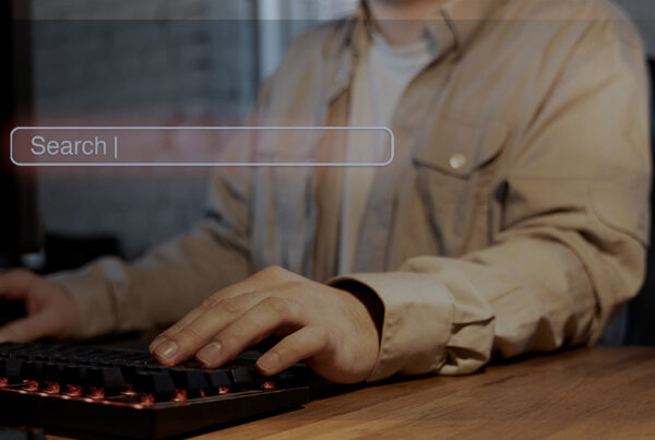 Pessoa digitando em um teclado com uma interface de barra de pesquisa flutuando à frente, sugerindo a escolha de um navegador de acordo com sua necessidade.