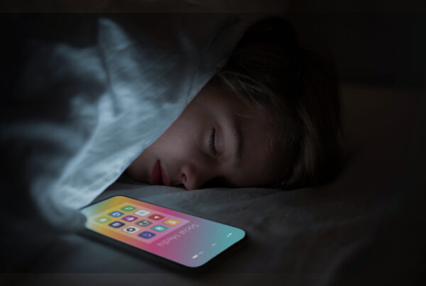Criança dormindo ao lado de um celular, refletindo os impactos da hiperconectividade e do uso excessivo de tecnologia na saúde mental.