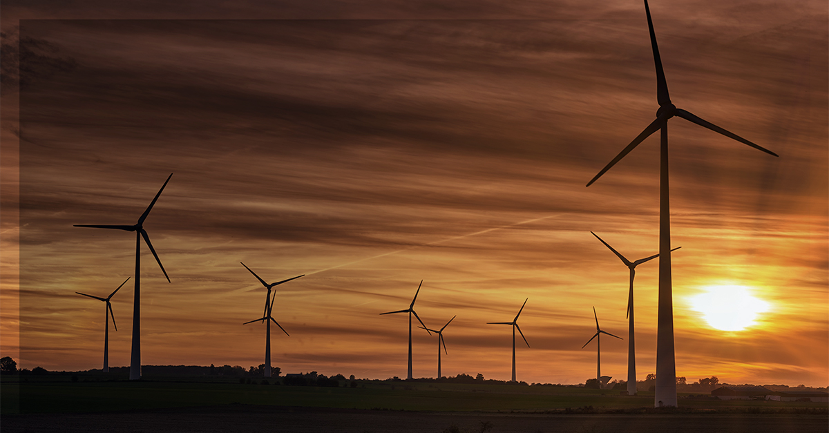 Parque eólico ao pôr do sol, destacando tecnologias sustentáveis para descarbonização e combate às mudanças climáticas.