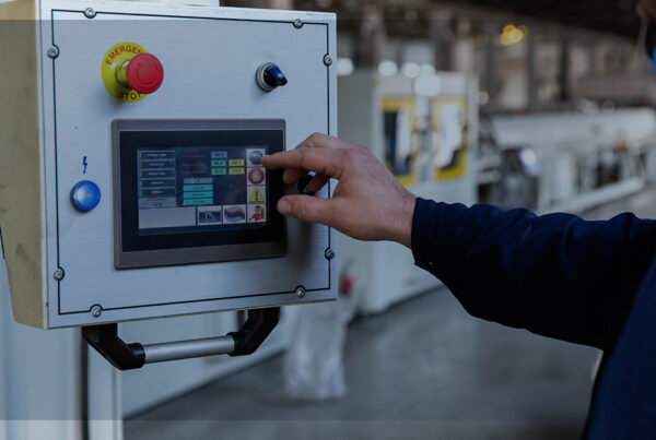 Pessoa usando um painel de controle com tela sensível ao toque em ambiente industrial, representando o uso de sensores inteligentes para monitoramento e automação.