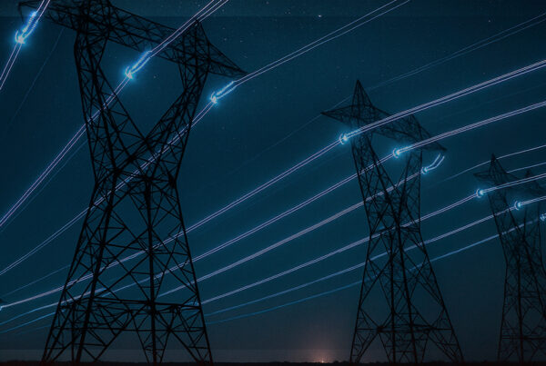 Torres de transmissão vistas à noite com trilhas de luz nos cabos, simbolizando a transmissão de dados e energia elétrica por PLC.