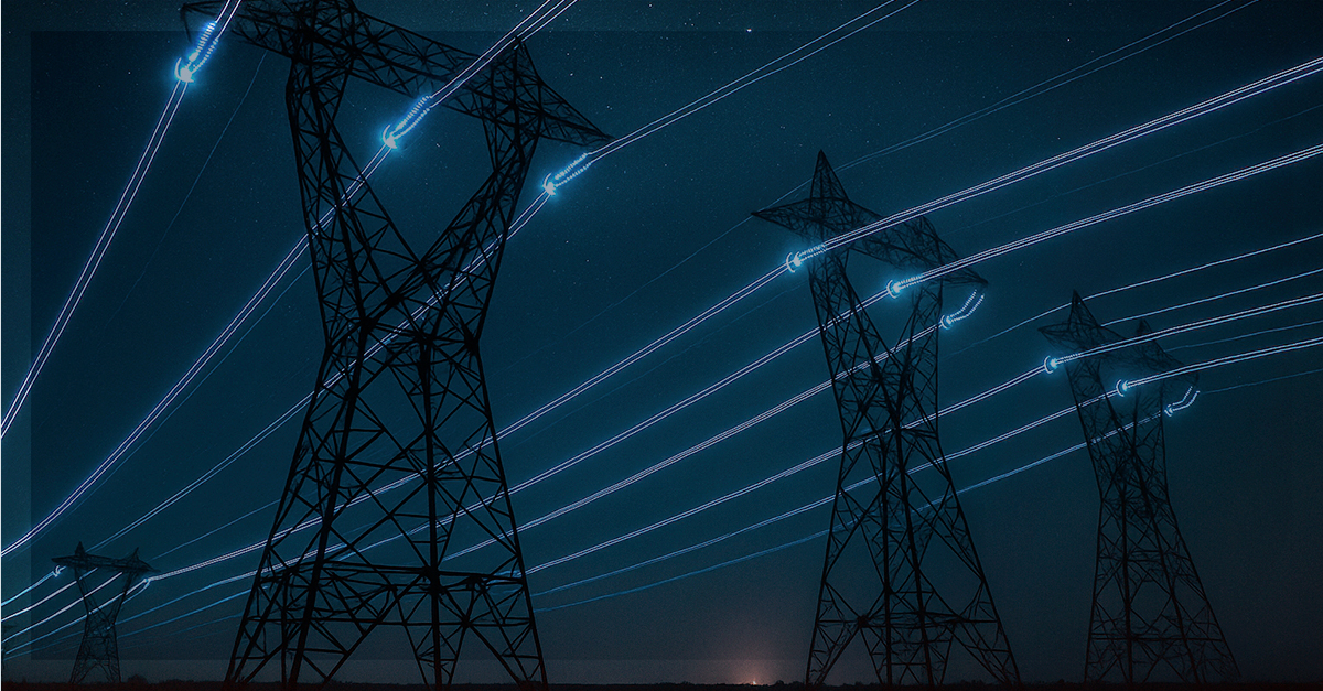 Torres de transmissão vistas à noite com trilhas de luz nos cabos, simbolizando a transmissão de dados e energia elétrica por PLC.