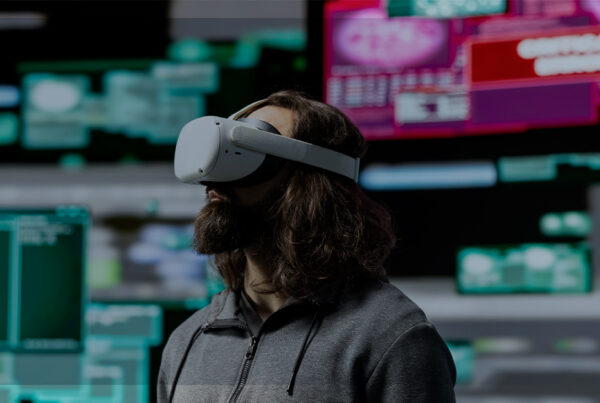 Homem usando headset de realidade virtual em sala com várias telas desfocadas ao fundo, exemplo de realidade estendida que combina AR, VR e MR.