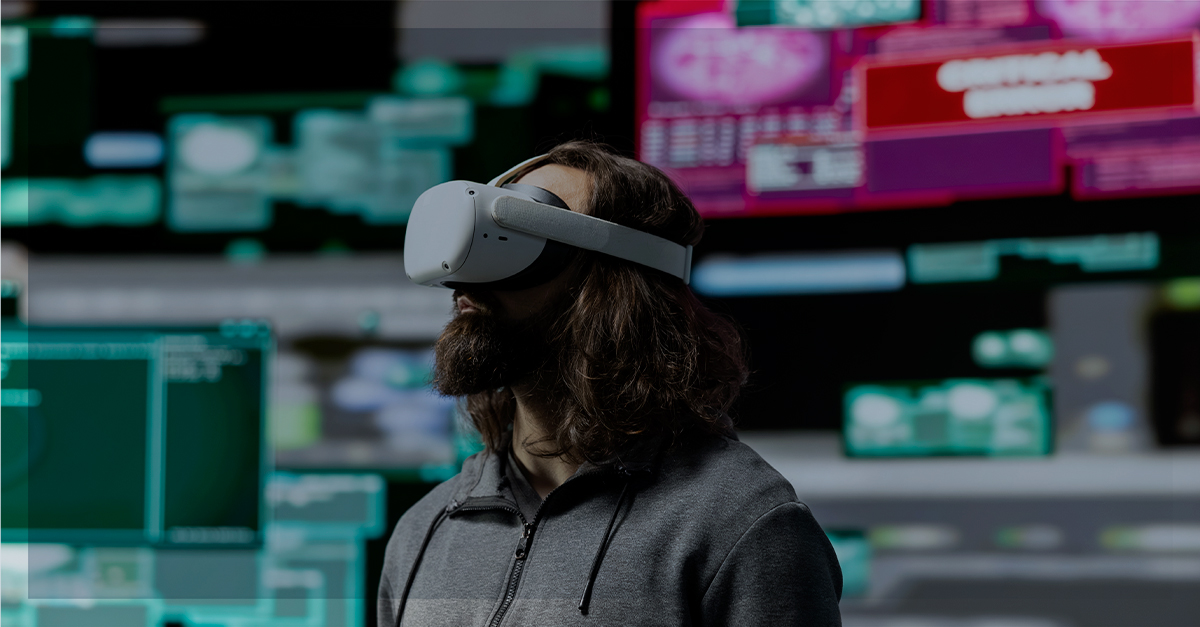 Homem usando headset de realidade virtual em sala com várias telas desfocadas ao fundo, exemplo de realidade estendida que combina AR, VR e MR.