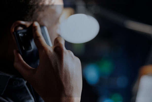 Pessoa ao telefone em ambiente escuro, ilustrando fraudes por telefone como spoofing e robocalls e a importância de proteger a operação