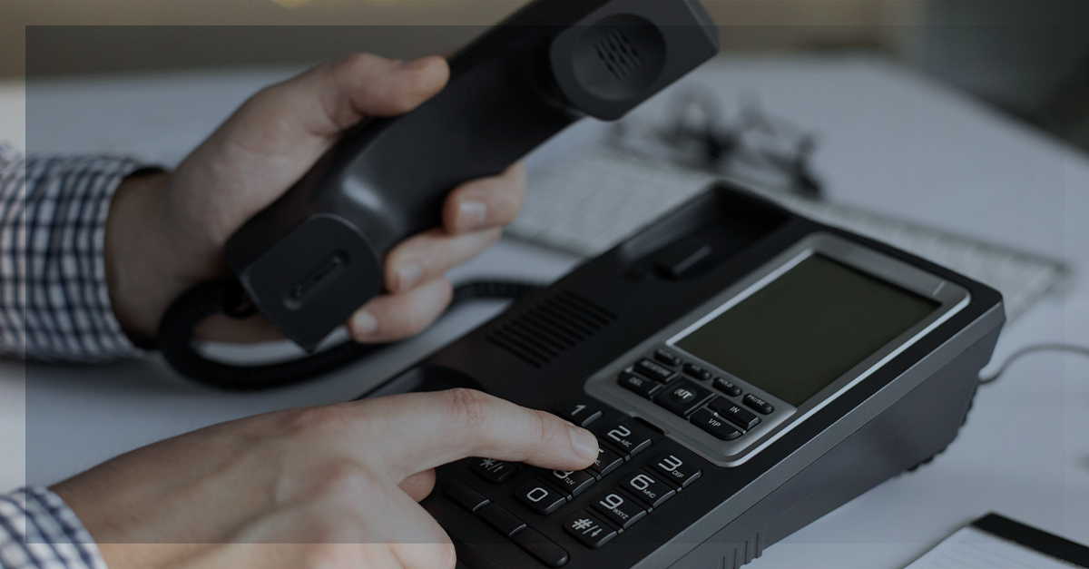 Ramais móveis: mão discando em telefone de mesa, representando mobilidade no atendimento corporativo.